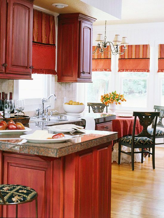 A bold red vintage kitchen with pretty cabinets, stone countertops and dark chairs and stools looks very classy and cool