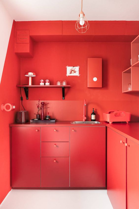 A strong red, solid kitchen with chic cabinets, shelves, back walls and worktops is completely red and looks expressive