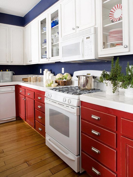 A bright kitchen with white and red cabinets, navy blue walls and white stone countertops is a stylish idea with light tones