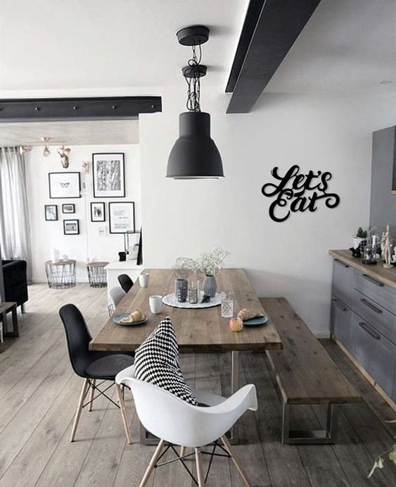 a graphite gray farmhouse kitchen with wooden countertops, a wooden table and bench, black chairs and pendant lamps