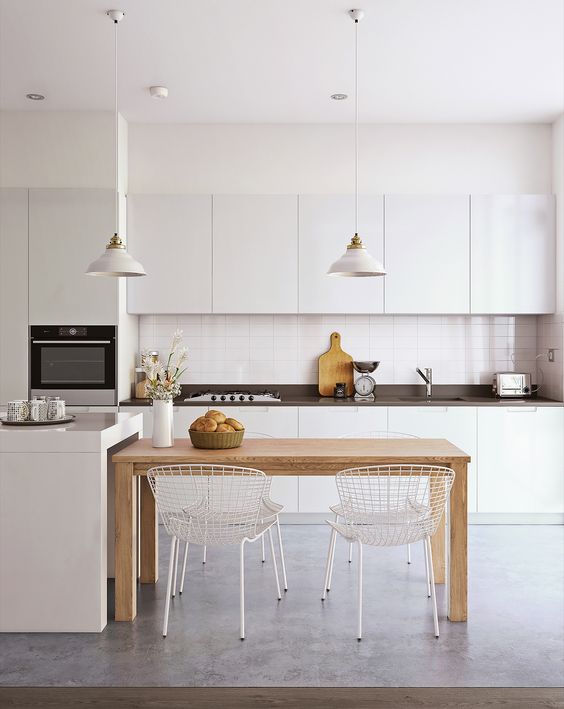 a minimalist kitchen in white with a black worktop, a small wooden table for contrast and a soft feel and metal chairs