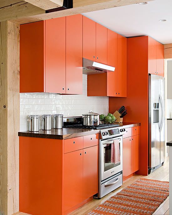 A matte orange kitchen with a white tile backsplash, a light carpet, and wooden countertops looks bright and cheerful
