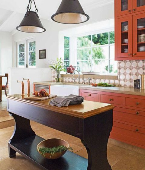 a sophisticated burnt orange kitchen with an aubergine island and black pendant lamps and brass accents