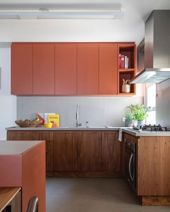 A stylish kitchen with elegant orange wooden upper and lower cabinets and an orange kitchen island looks very trendy