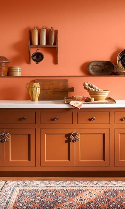 A terracotta kitchen with burnt orange walls and white stone countertops is a stylish and chic space