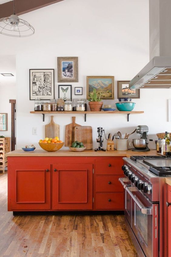 A vintage farmhouse kitchen in neutral tones but with burnt orange cabinets, light stained countertops and a pretty gallery wall
