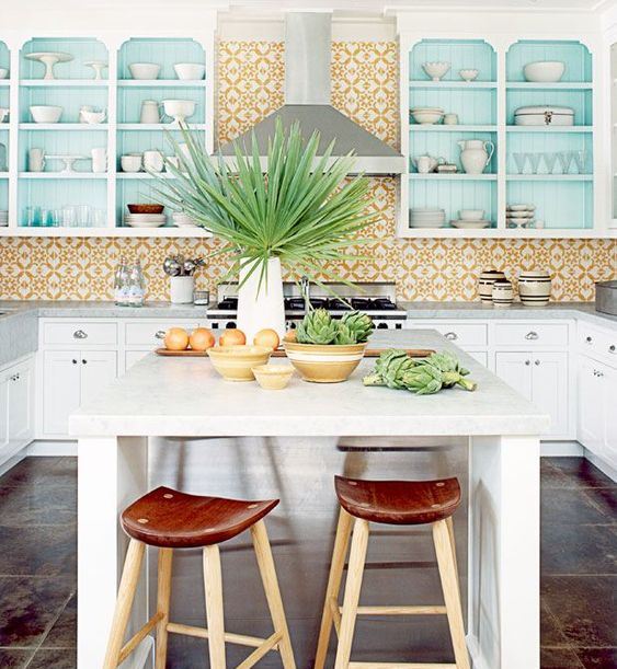 a bright and fun kitchen with a yellow tile backsplash, blue cabinets and an island with wooden stools