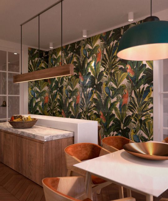 a colorful tropical kitchen with an eye-catching statement wall, an eye-catching kitchen island with two countertops, a wooden pendant lamp and a cozy dining area