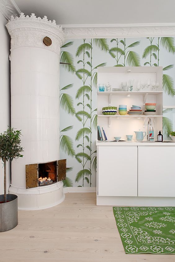 a creative tropical kitchen with tropical wallpaper, white minimalist cabinets, a fireplace and a printed rug