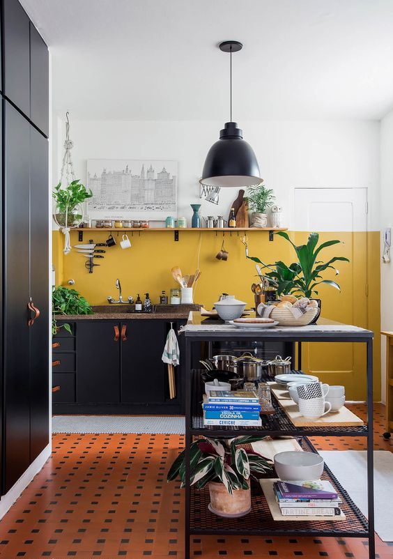 a black kitchen with stone countertops and a mustard-colored block wall for a bright touch