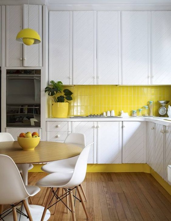 a modern white kitchen with a striped pattern and a lemon yellow tile backsplash and a matching pendant light