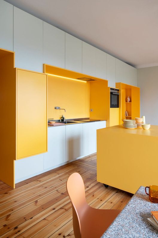 A bright white kitchen with sunny yellow niches and a kitchen island looks very cheerful