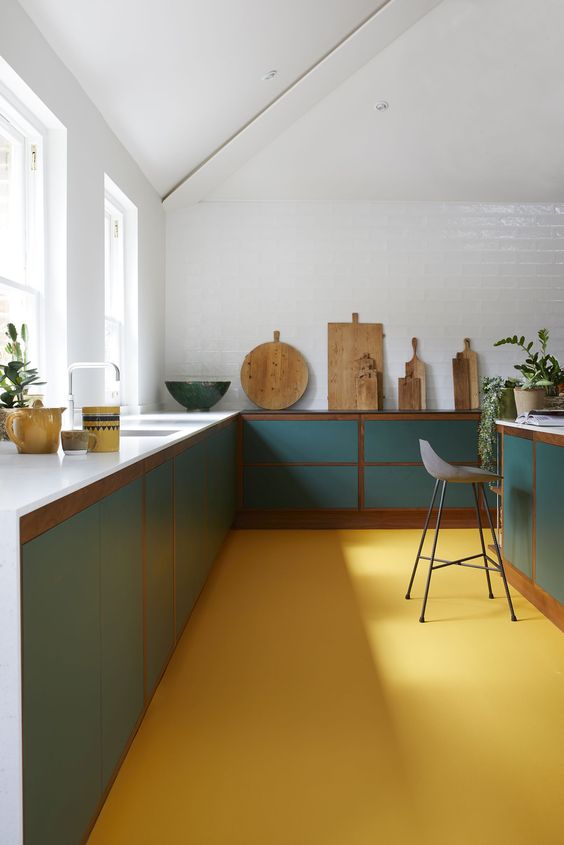 a bright mid-century modern kitchen with teal cabinets and a yellow floor that warms the space