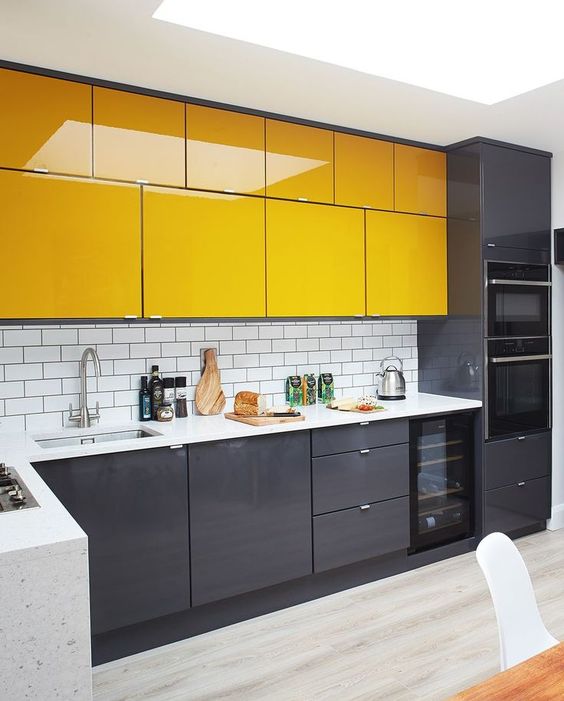 A modern kitchen in graphite gray and yellow, with a white subway tile backsplash and white stone countertop