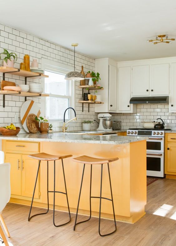A neutral boho kitchen with white upper cabinets and yellow lower cabinets adding color and warmth to the room