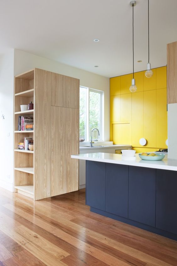 A stylish, minimalist kitchen in white, yellow and navy blue without handles looks bright and bold