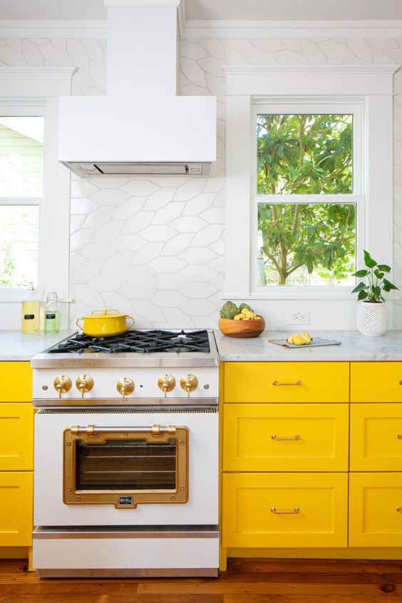 A vibrant yellow kitchen with white tiles and neutral stone countertops creates a fresh and airy feel