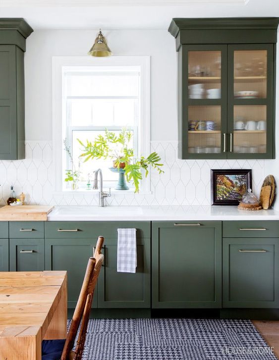 A chic modern farmhouse kitchen in dark green with a striking white tile backsplash and touches of brass