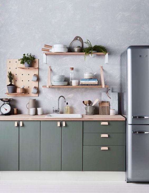 A modern dark green kitchen with a wallpaper wall, plywood shelves and a gray refrigerator is chic and stylish