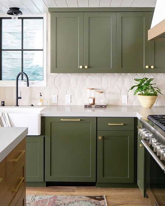 a grass green kitchen with gold and brass accents, black fixtures and a striking geometric tile backsplash