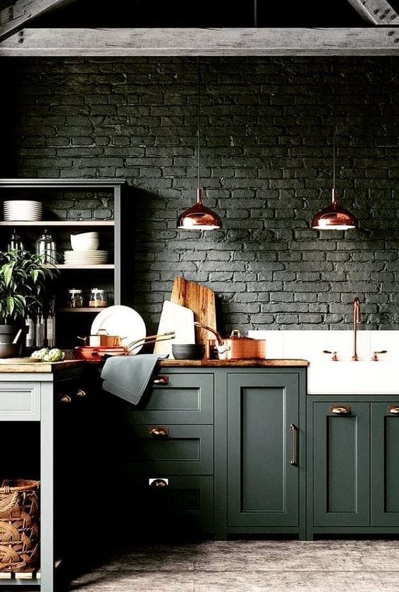 A moody hunter green kitchen with brick walls, stained wood countertops and copper items for a delicate touch