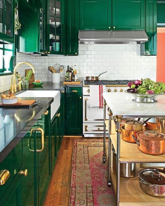 a glossy, glamorous emerald green kitchen, white subway tile backsplash, black countertops, and gold and brass accents