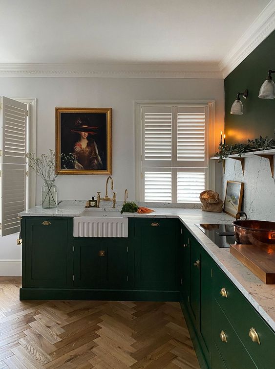 A stylish vintage-inspired emerald green kitchen with a white marble backsplash and countertops and gold accents