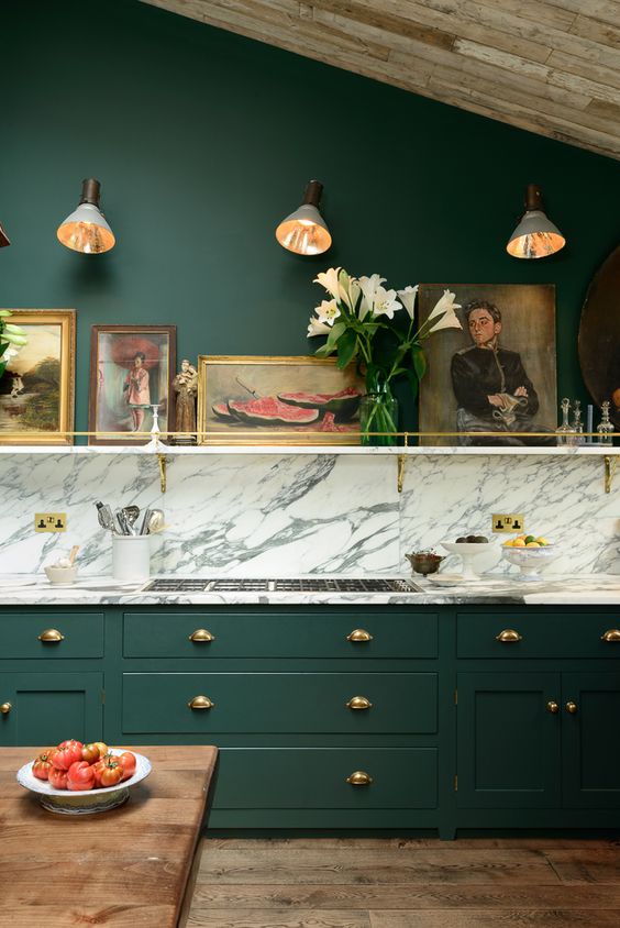 A very elegant and chic vintage hunter green kitchen with a white marble backsplash and touches of gold