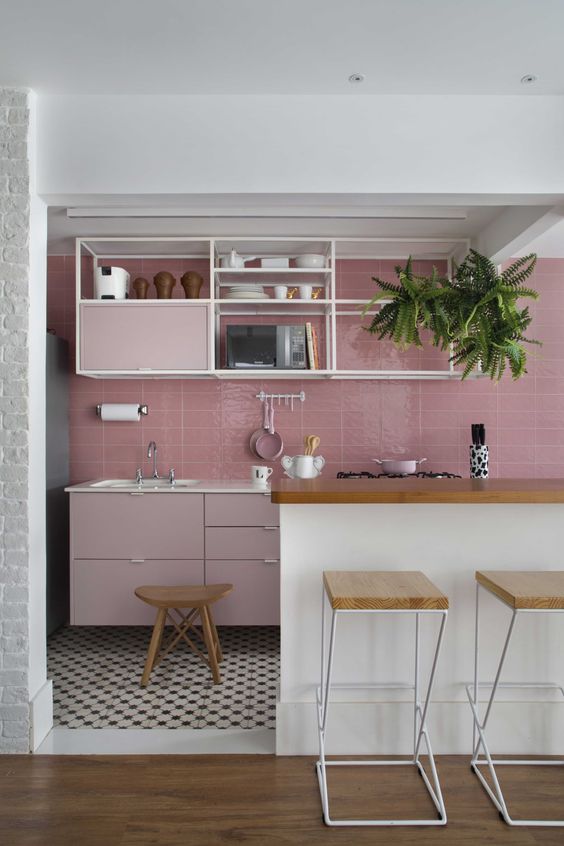 a striking kitchen with a pink tile backsplash and pale pink cabinets, open shelving and a large white kitchen island