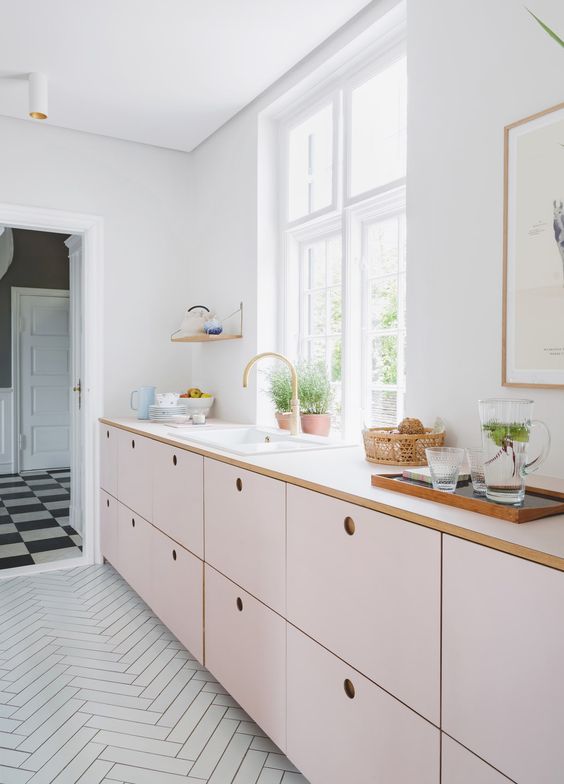 a delicately blushed kitchen with only base cabinets and white countertops, as well as plenty of natural light