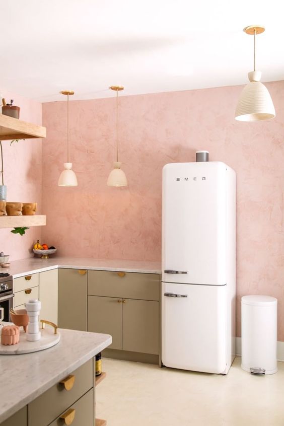 an inviting kitchen with pink walls, green cabinets, gold handles, pendant lamps and open shelves