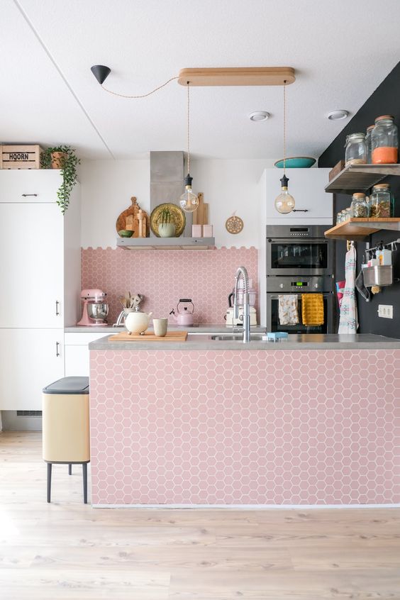 An airy kitchen with white cabinets and a large pink hexagon tile backsplash and kitchen island is truly amazing