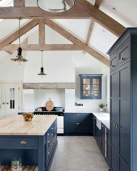 a navy blue kitchen with a white backsplash, countertops, a large island with a wooden countertop and wooden beams