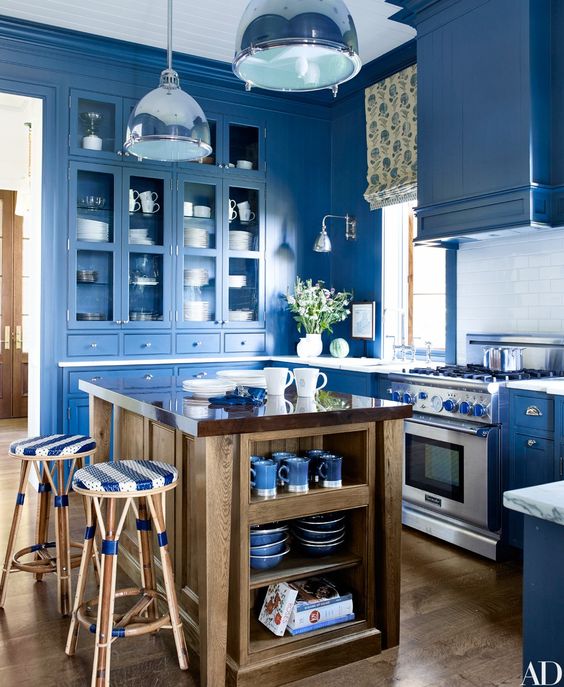 a super bright blue kitchen with a white subway tile backsplash, pendant lamps, a printed shade and a wooden kitchen island