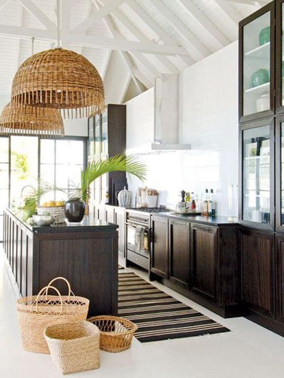 a chic tropical kitchen with dark-stained cabinets, baskets, wicker lampshades, tropical plants and a striped rug