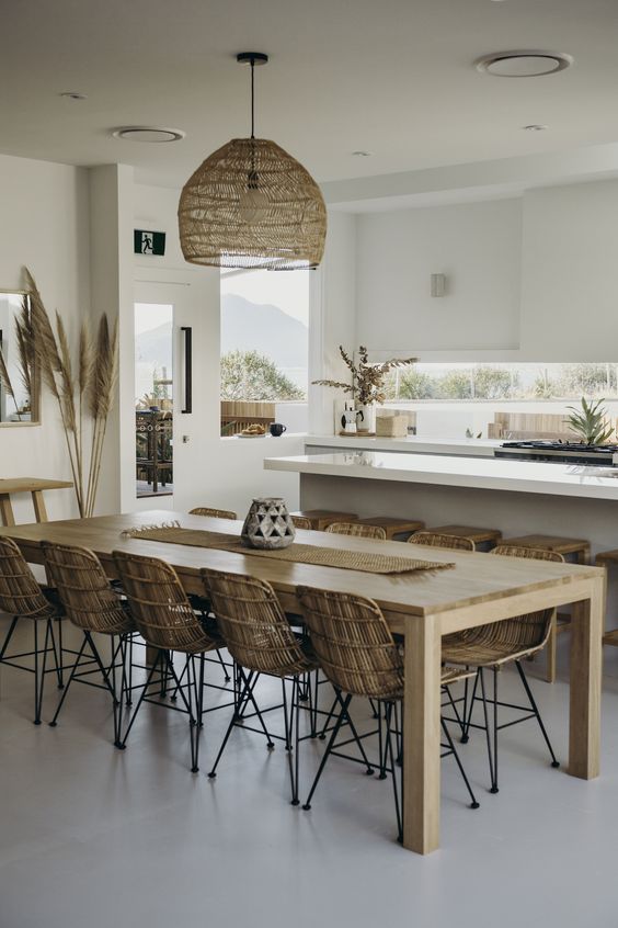 a tropical kitchen with sleek white cabinets, a wicker lampshade, rattan chairs, tropical plants and pampas grass