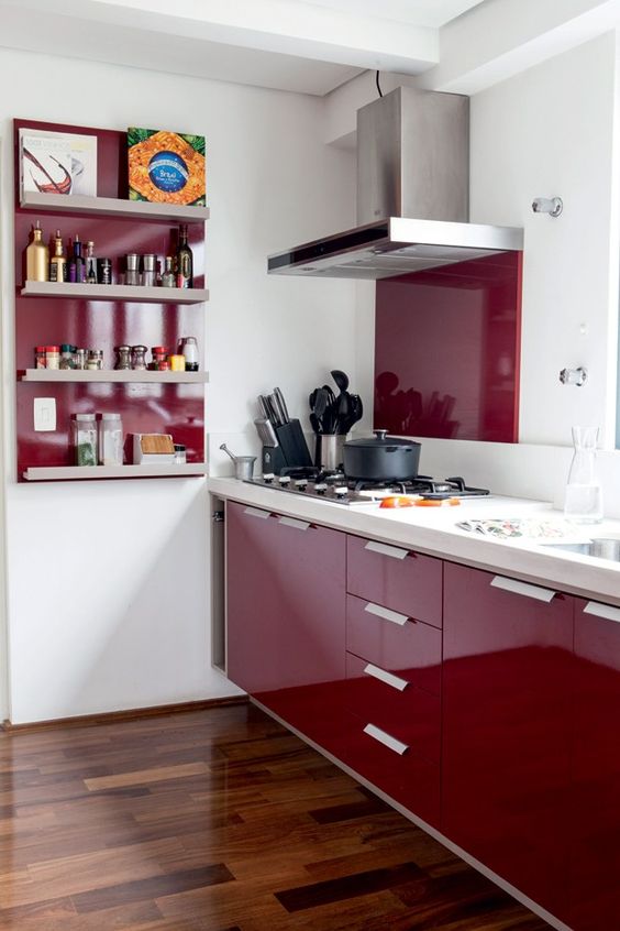 A beautiful modern kitchen in deep burgundy with a white worktop and backsplash, burgundy backsplash and shelf