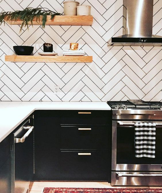 a black farmhouse kitchen with white countertops, a herringbone backsplash with black grout and floating shelves
