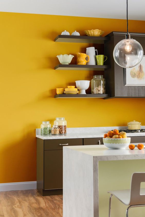 A sunny yellow accent wall brightens up a brown and neutral kitchen, making it bold and cool