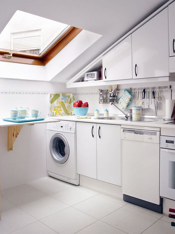 a tiny attic kitchen with elegant cabinets, a small folding table, colorful dishes and a skylight