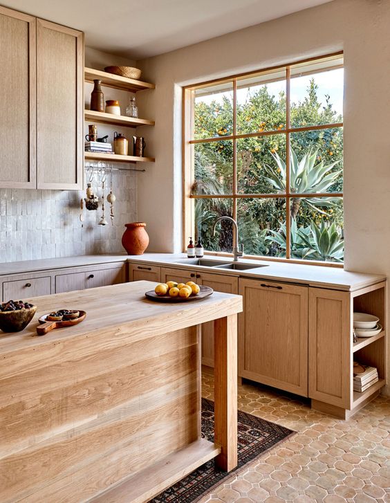 a beautiful Mediterranean kitchen with light stained cabinets, stone countertops, an island and open shelving