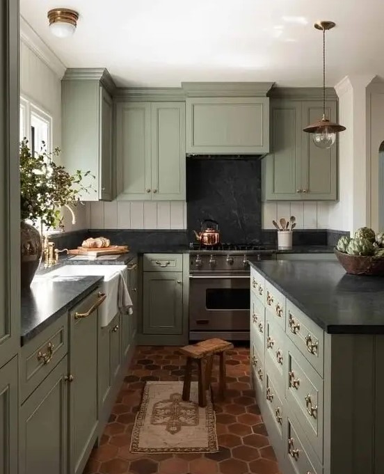 a sage green kitchen with black stone countertops and a beadboard backsplash and terracotta tiles