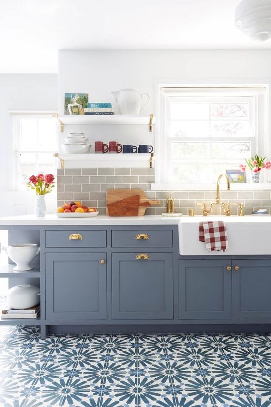 A beautiful blue Shaker-style kitchen with a gray subway tile backsplash, white quartz countertops, and brass accents