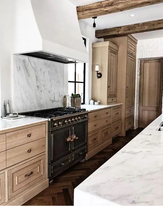 a beautiful and sophisticated kitchen with light stained cabinets, a white extractor hood and white marble backsplash and worktops