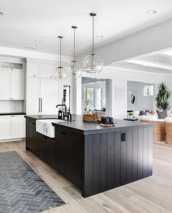 a white kitchen with shaker cabinets, a black slat kitchen island, and glass ball pendant lights