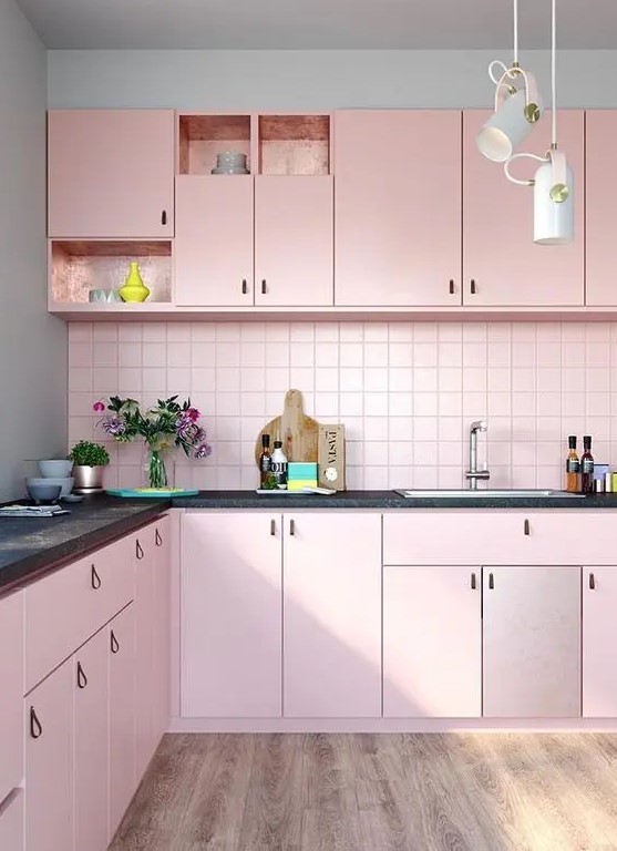 a pretty pastel pink kitchen with leather handles, a matching pink splashback and black worktops