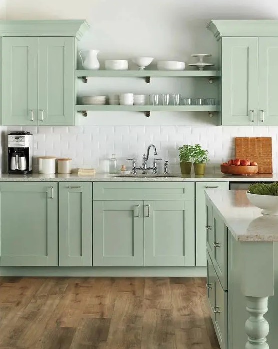 A beautiful farmhouse kitchen in mint green with shaker cabinets, open shelving, white subway tiles and vintage furnishings