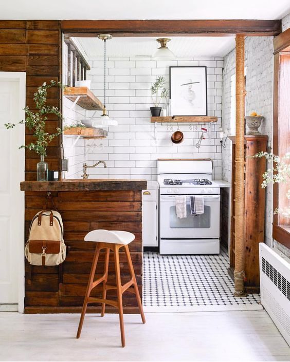 a tiny white kitchen with richly stained wood surfaces, potted plants and a mosaic tile floor
