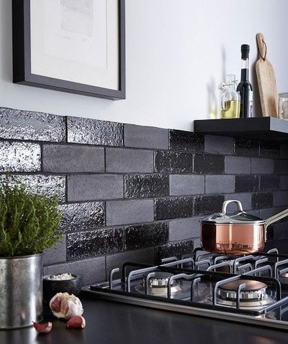 A black backsplash with glossy and matte faux bricks is a cool and fresh modern idea to try