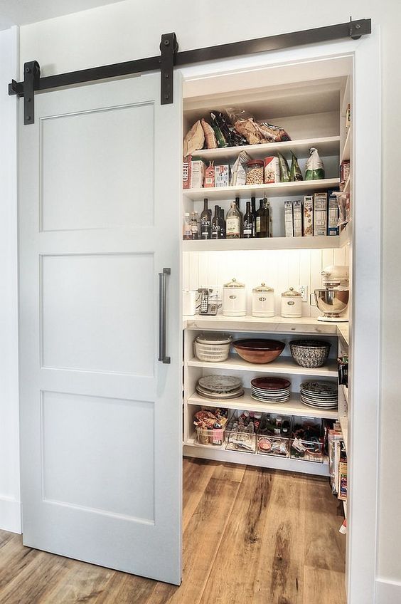 A modern farmhouse-style pantry with barn doors, lights, and open shelves is a cool and well-organized storage space